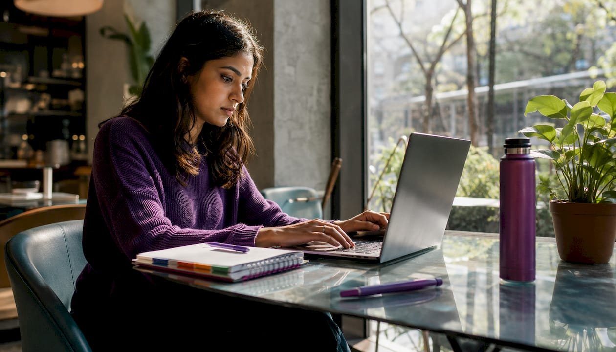 Freelancer typing proposal on laptop at home